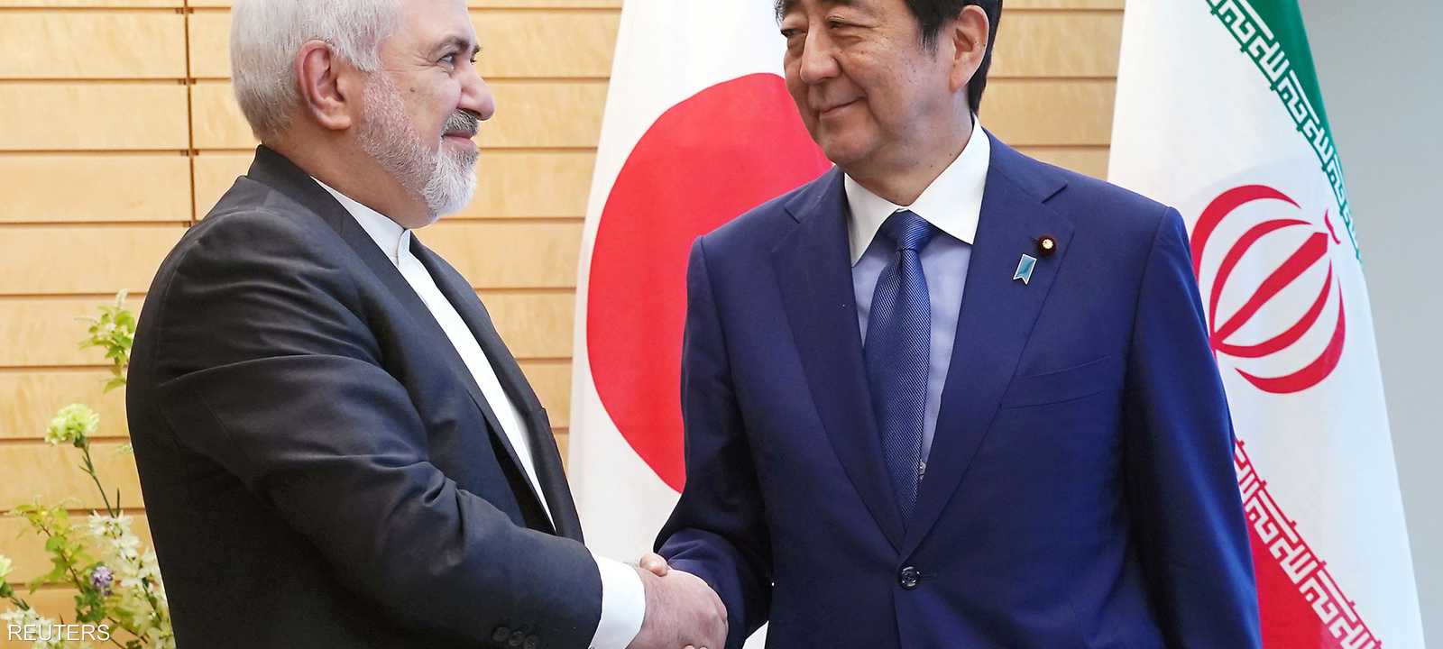 آبي مصافحا ظريف خلال زيارة الأخير لطوكيو في مايو الماضي