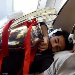 توثق الصورة صلاح نائما في الطائرة ومحتضنا كأس أبطال أوروبا