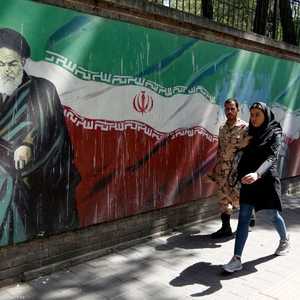 إيرانيون يمرون قرب جدارية العلم والخميني بطهران