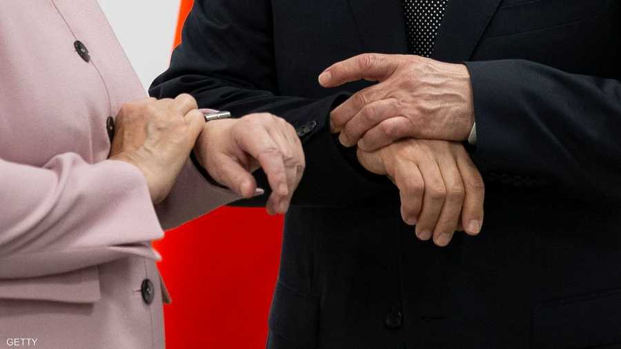 بوتن وميركل ينظران إلى ساعتي اليد في وقت واحد