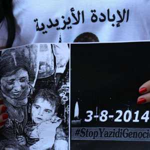 إيزيدية تحمل بطاقة تذكر بما حل بأبناء طائفتها على أيدي داعش