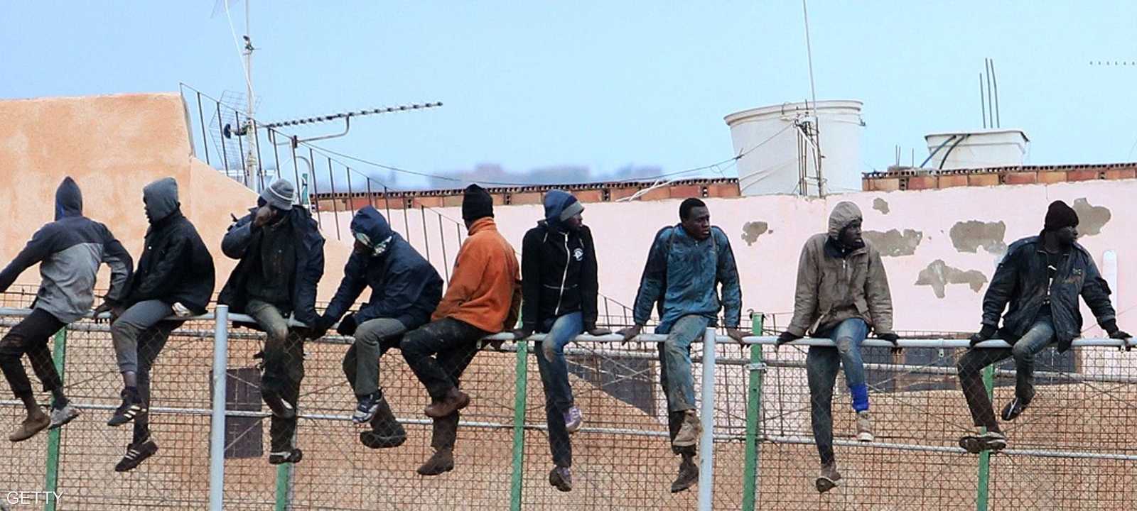 مهاجرون يتسلقون السياج بين مليلية وإسبانيا.