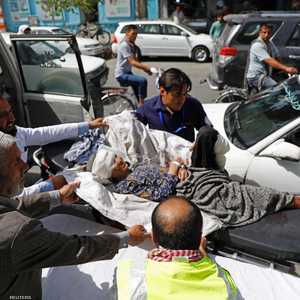 ينقلون سيدة أصيبت في الانفجار الذي هز كابل، الأربعاء.