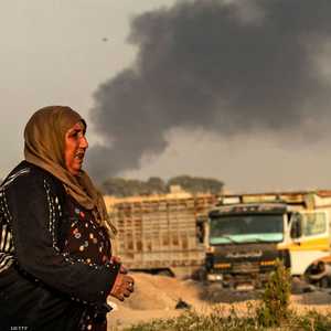 سيدة سورية تركض هربا من الغارات التركية