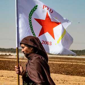 امرأة كردية سورية تلوح بعلم حزب الاتحاد الديمقراطي الكردي