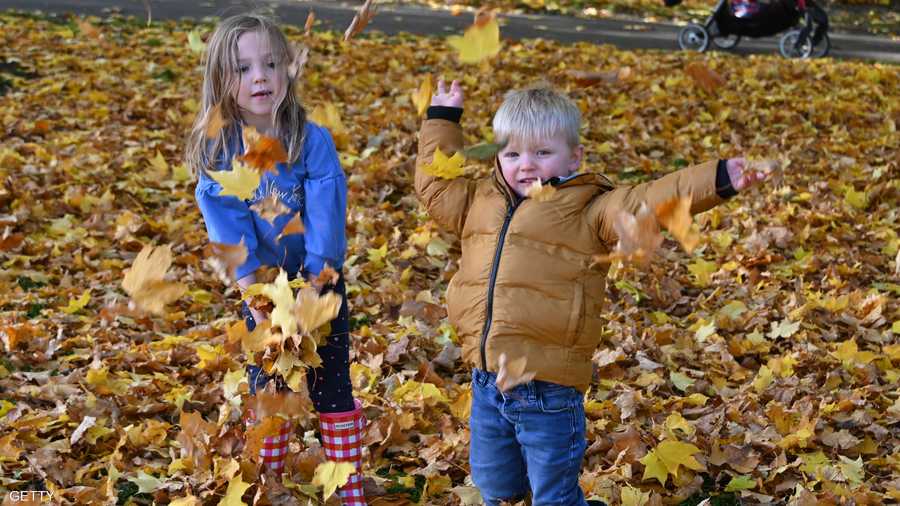 ديفيس موريسون (سنتان) وشقيقته إيسلا روز (5 سنوات) من غلاسكو في اسكتلندا يستمتعان بأوراق الخريف بجانب إحدى البحيرات.