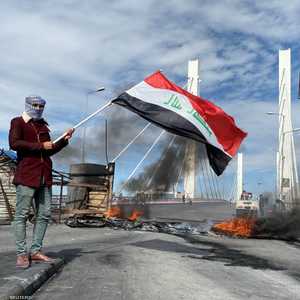 متظاهر عراقي يرفع علم بلاده في الناصرية جنوب العراق