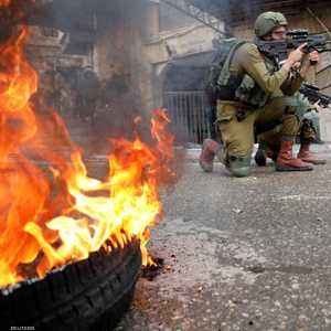 جندي إسرائيلي يصوب بندقيته على متظاهرين فلسطينيين في الخليل