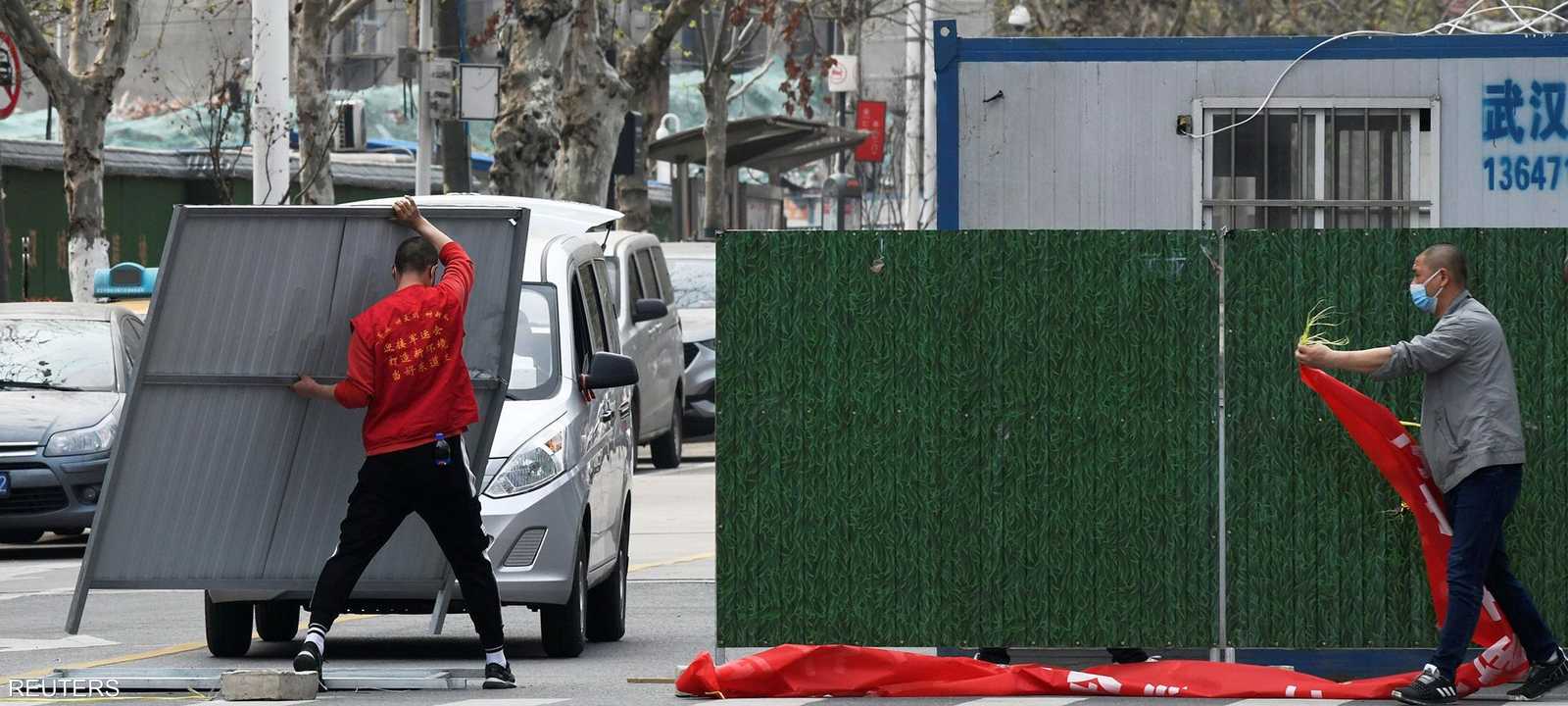 عمال يزيلون الحواجز البلاستيكية في ووهان مع تخفيف القيود