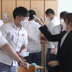 معلمة تقيس درجة الحرارة لطالب بعد إعادة فتح المدارس.