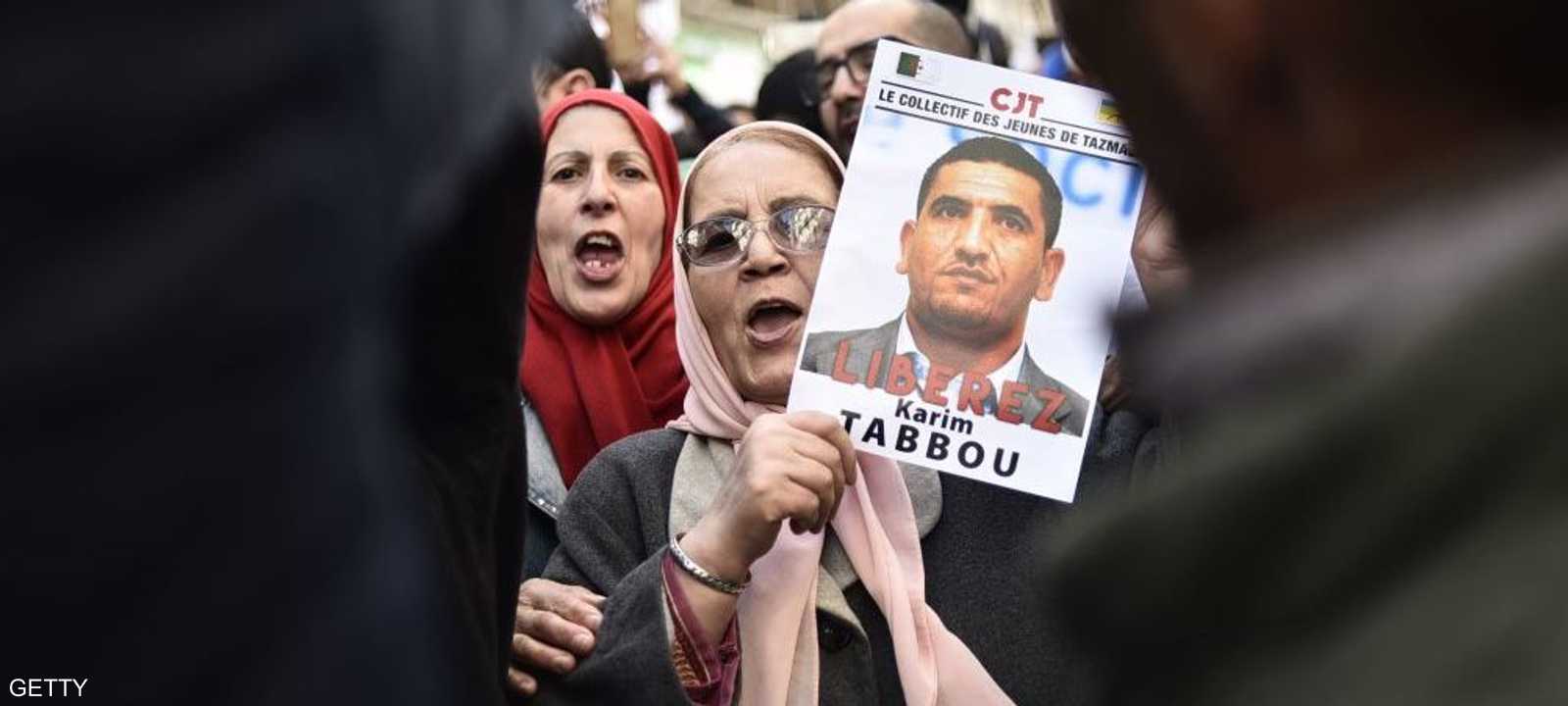 متظاهرة ترفع صورة الناشط كريم طابو مطالبة بالإفراج عنه.