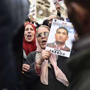 متظاهرة ترفع صورة الناشط كريم طابو مطالبة بالإفراج عنه.