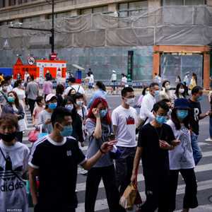 أشخاص يضعون كمامات يسيرون في أحد شوارع شنغهاي.