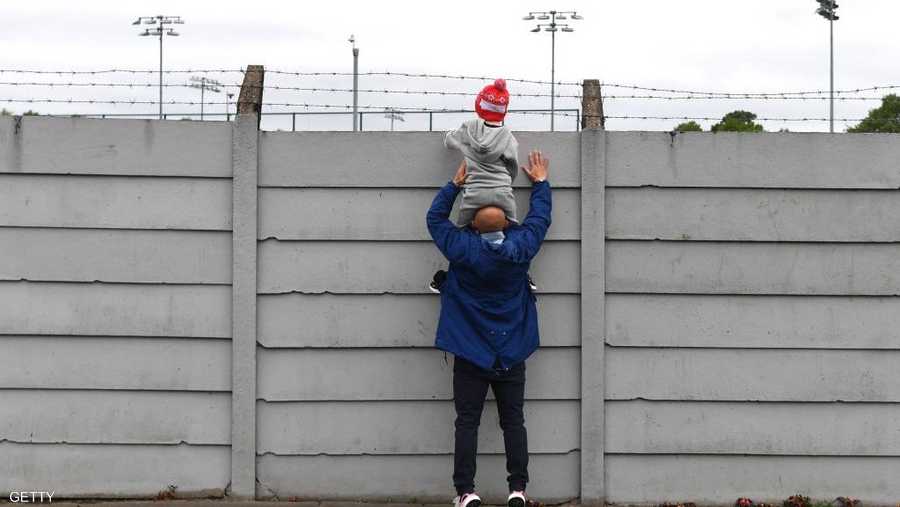 أب يحمل ابنه لمشاهدة تدريبات فريقه المفضل ليفربول.