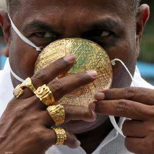 يضع رجل هندي كمامة مصنوعة من الذهب