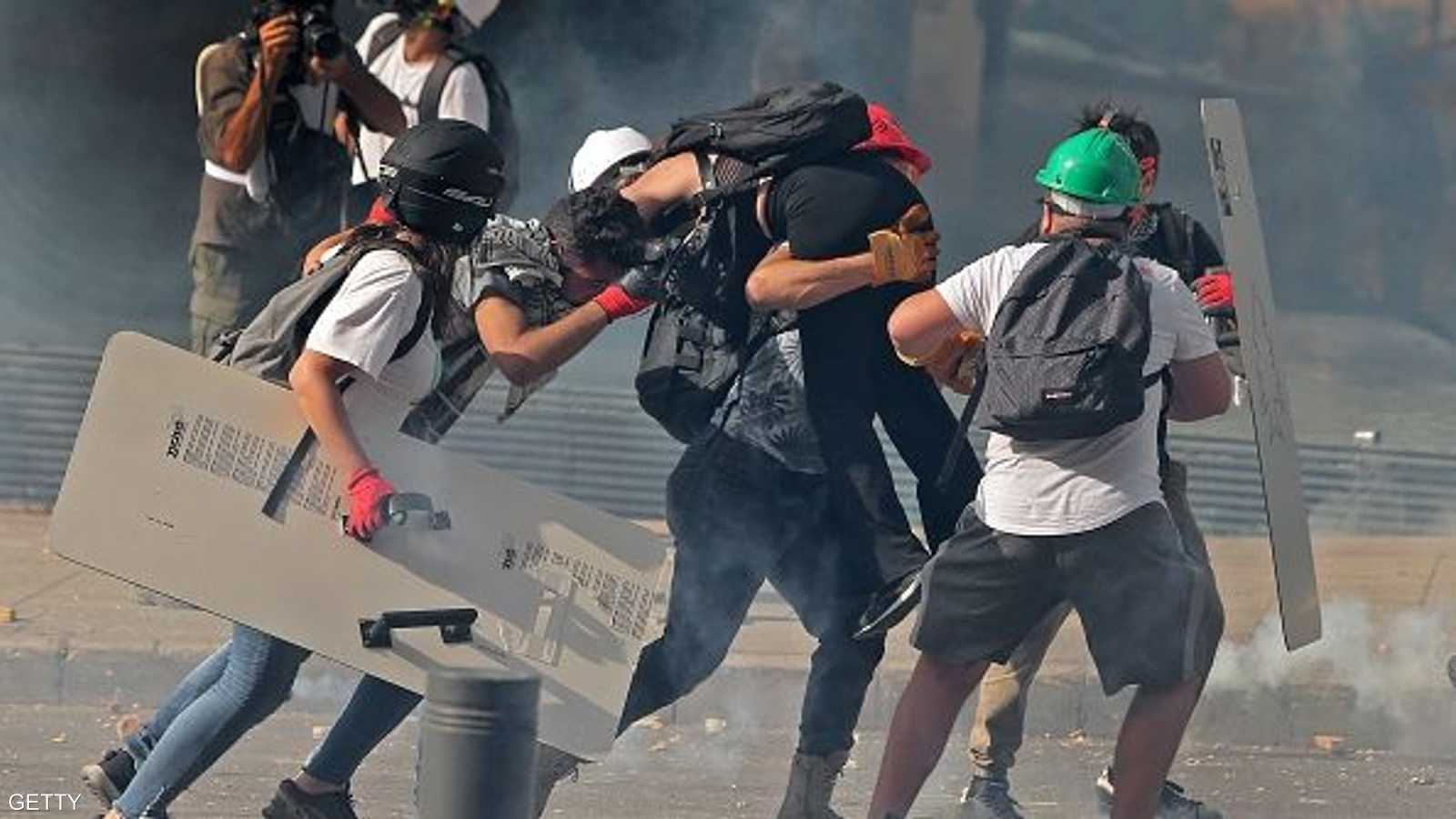 متظاهرون يحملون جريحا جراء الاشتباكات مع الشرطة