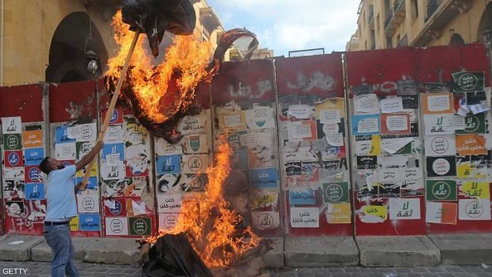 متظاهر يقذف بلافتة مشتعلة خلف الجدار الأمني