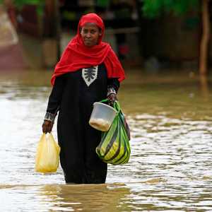 سيدة سودانية تتحدى الفيضانات لشراء حاجيات المنزل