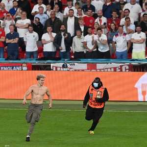 رجال الأمن يلاحقون أحد المشجعين الذين اقتحموا ملعب ويمبلي.