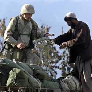 صورة أرشيفية لأفغاني خلال مساعدته لجندي أميركي