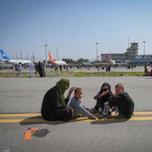 عائلة أفغانية تجلس على أحد مدارج مطار كابل