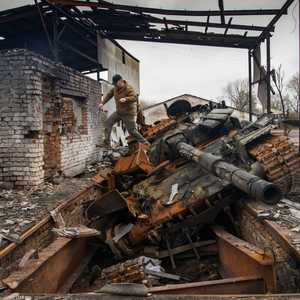 رجل يقفز فوق دبابة روسية دمرت في حرب أوكرانيا.