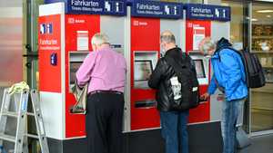 مسافرون يقفون أمام آلة بيع تذاكر قطار دويتشه - ألمانيا