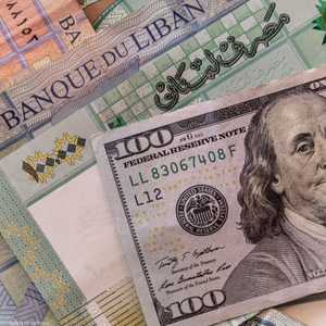 العملة اللبنانية مع ورقة من فئة 100 دولار أميركي