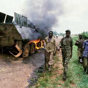 مقاتلو المقاومة الوطنية بأوغندا يقفون أمام عربة محترقة للجيش