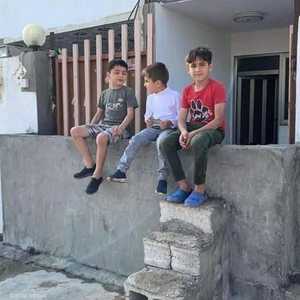 أطفال عراقيون يجلسون على جدار بني أمام منزل في إقليم كردستان