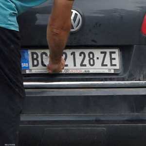 سائق يزيل ملصقًا يغطي العلامة الوطنية على لوحة سيارته