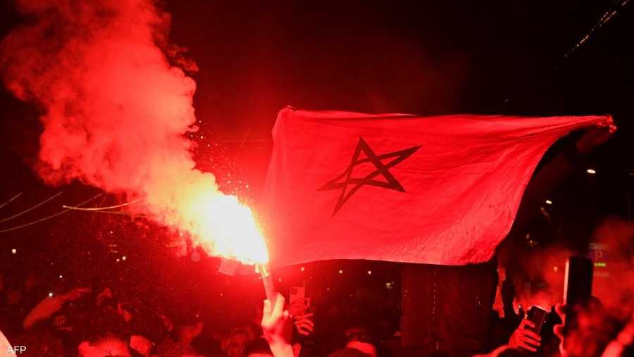المشجعون في حي رافال ببرشلونة وهم يلوحون بالأعلام المغربية، ويشعلون الألعاب النارية