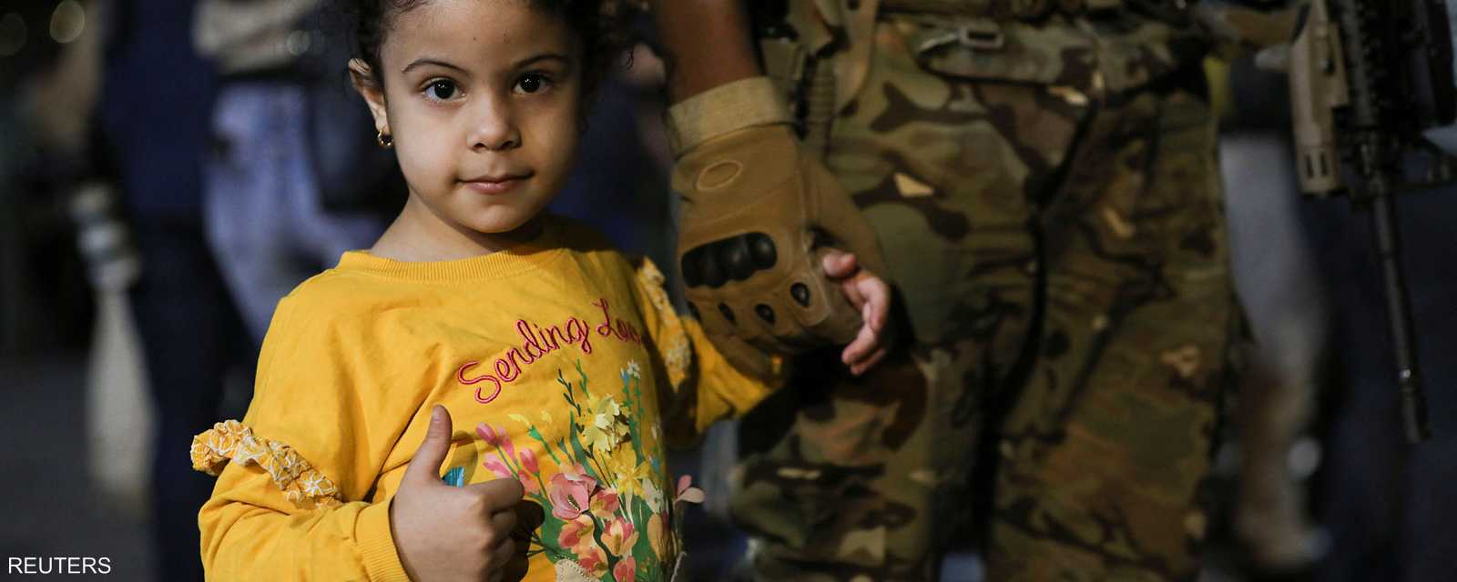 جندي أردني يمسك بيد طفلة من عائلات القادمين