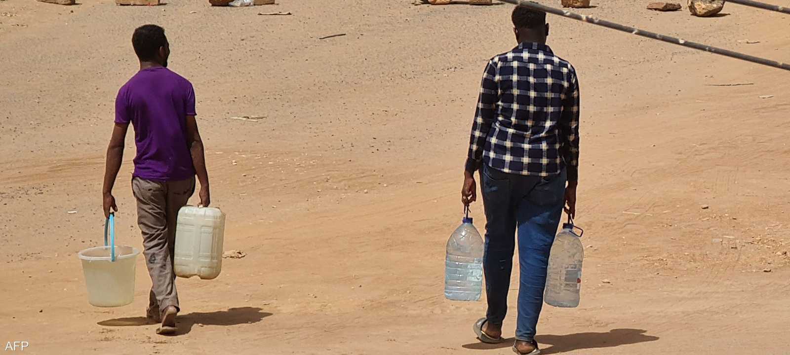 سودانيون يحملون زجاجات مياه عائدين إلى منزلهم في الخرطوم