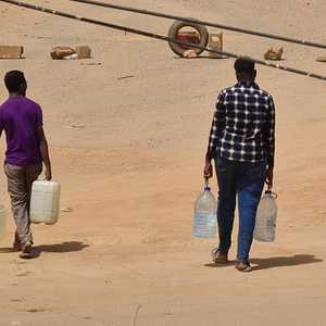 سودانيون يحملون زجاجات مياه عائدين إلى منزلهم في الخرطوم