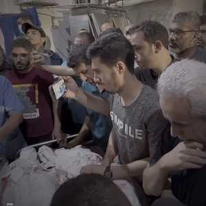 يوسف النجار (يمين) وهو في حالة صدمة أمام جثامين زوجته وأطفال