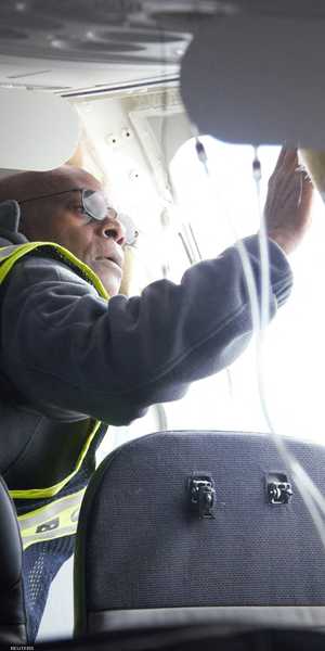 أحد الفنيين يتفقد الخلل في مخرج الطوارئ للطائرة