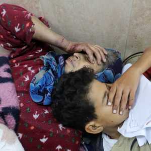 طفل يتكئ على كتف والدته الجريحة بعد قصف إسرائيلي لدير البلح