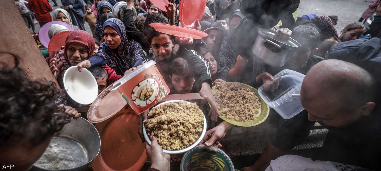 فلسطينيون يتجمعون للحصول على الطعام في مدرسة بمدينة رفح