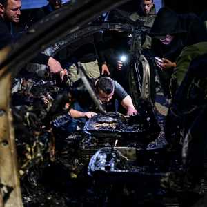 فلسطينيون يتجمعون أمام السيارة التي تم قصفها