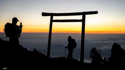 سياح يشاهدون شروق الشمس من فوق قمة جبل فوجي