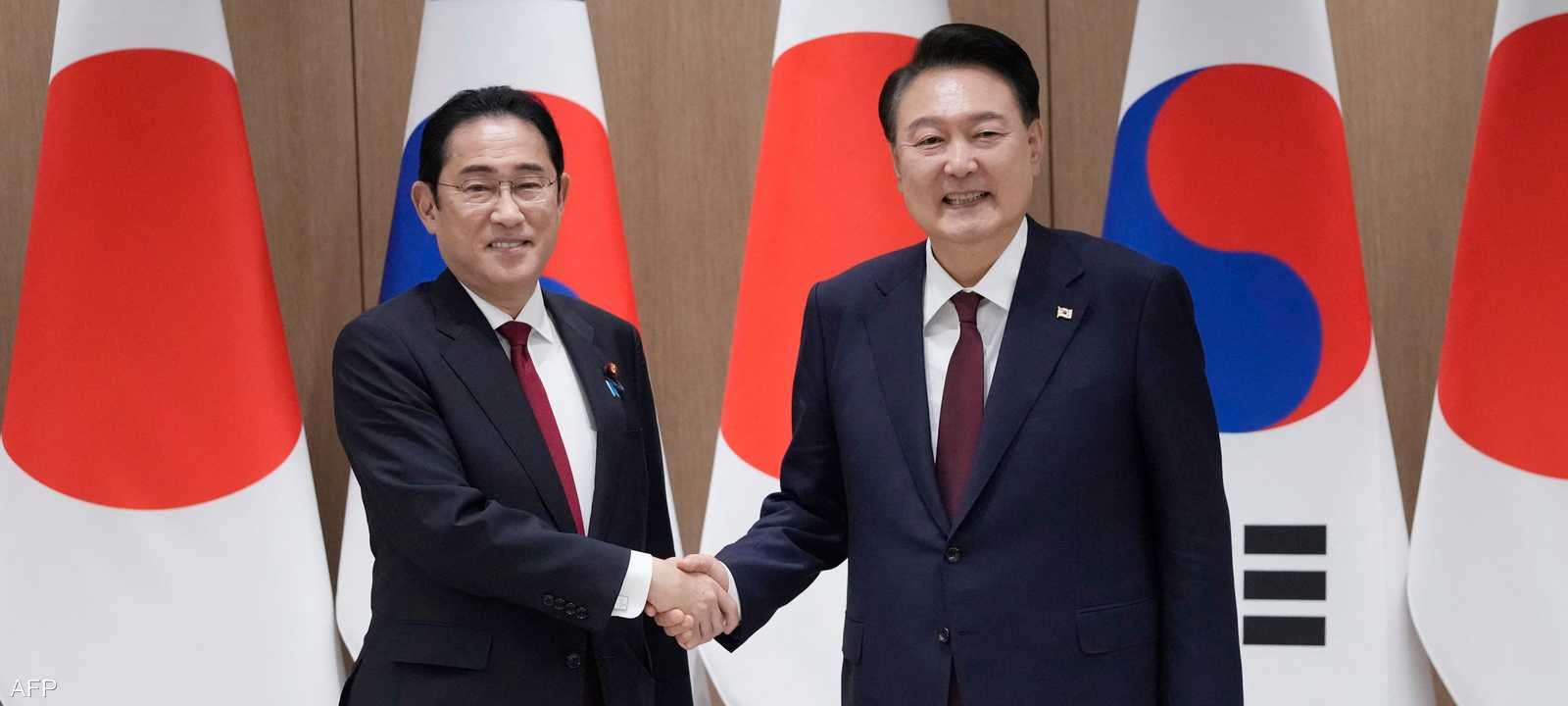 رئيس كوريا الجنوبية يصافح رئيس الوزراء الياباني