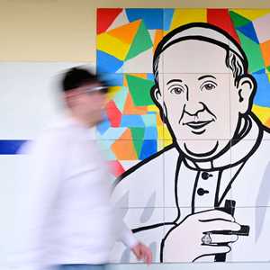 رجل يمشي أمام صورة للبابا في مستشفى جيميلي الجامعي