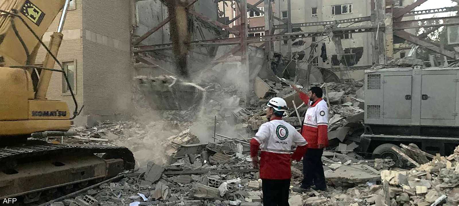 أعضاء من فرق الإنقاذ أمام مبنى دمر في هجوم إسرائيلي بطهران