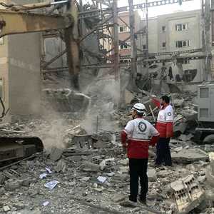 أعضاء من فرق الإنقاذ أمام مبنى دمر في هجوم إسرائيلي بطهران