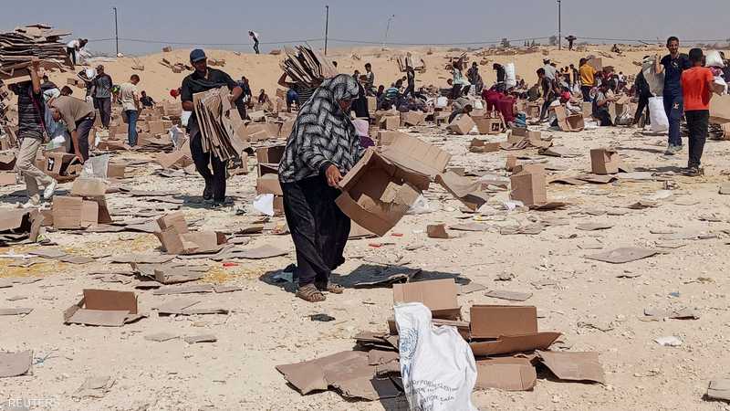 سيدة تبحث عن شيء يؤكل بموقع لتوزيع المساعدات في غزة