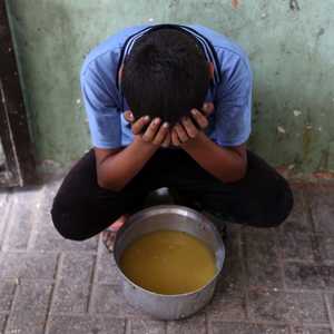 طفل فلسطيني مع حصته من شوربة العدس من مركز مساعدات في غزة