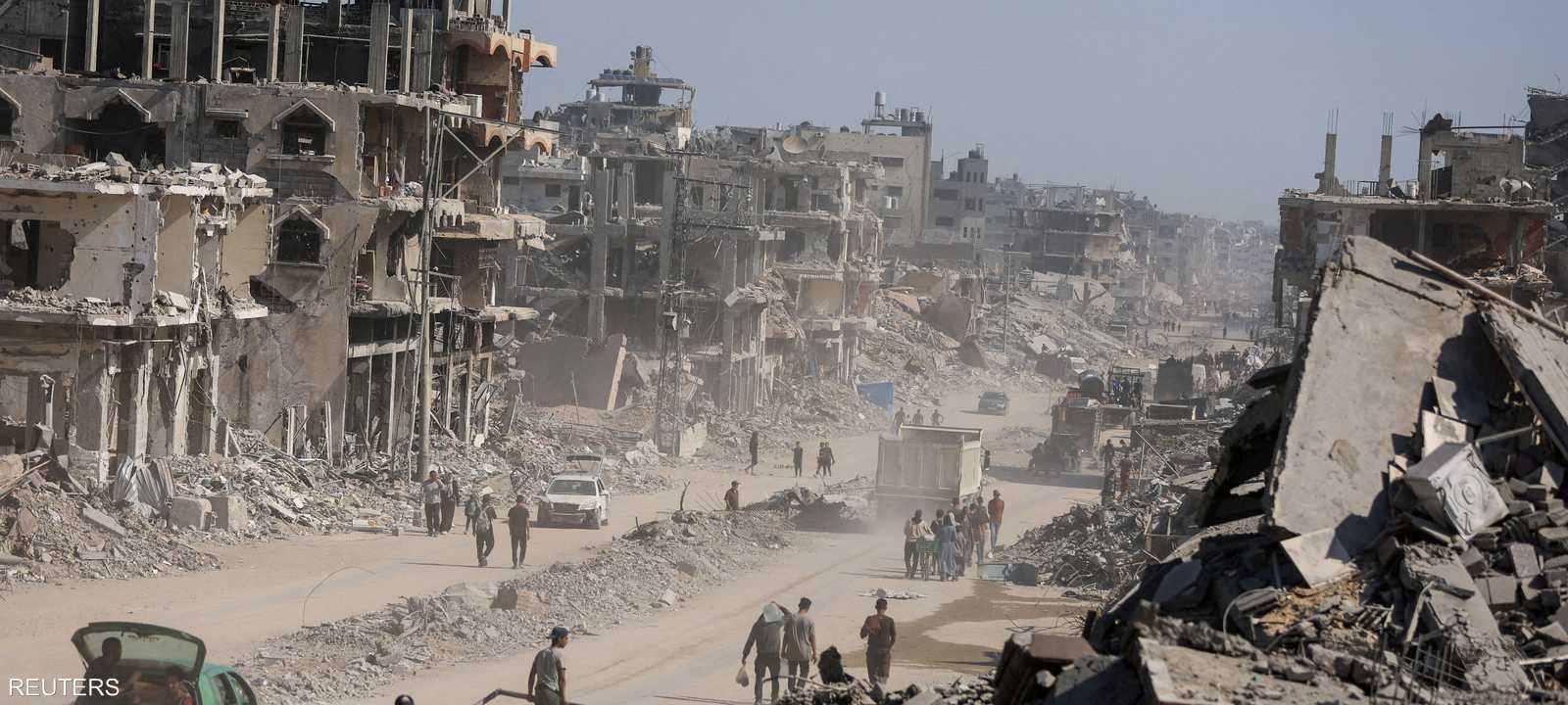 فلسطينيون يسيرون بين أنقاض المباني المدمرة في غزة