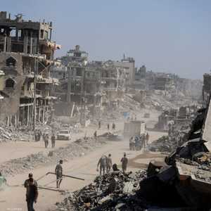 فلسطينيون يسيرون بين أنقاض المباني المدمرة في غزة