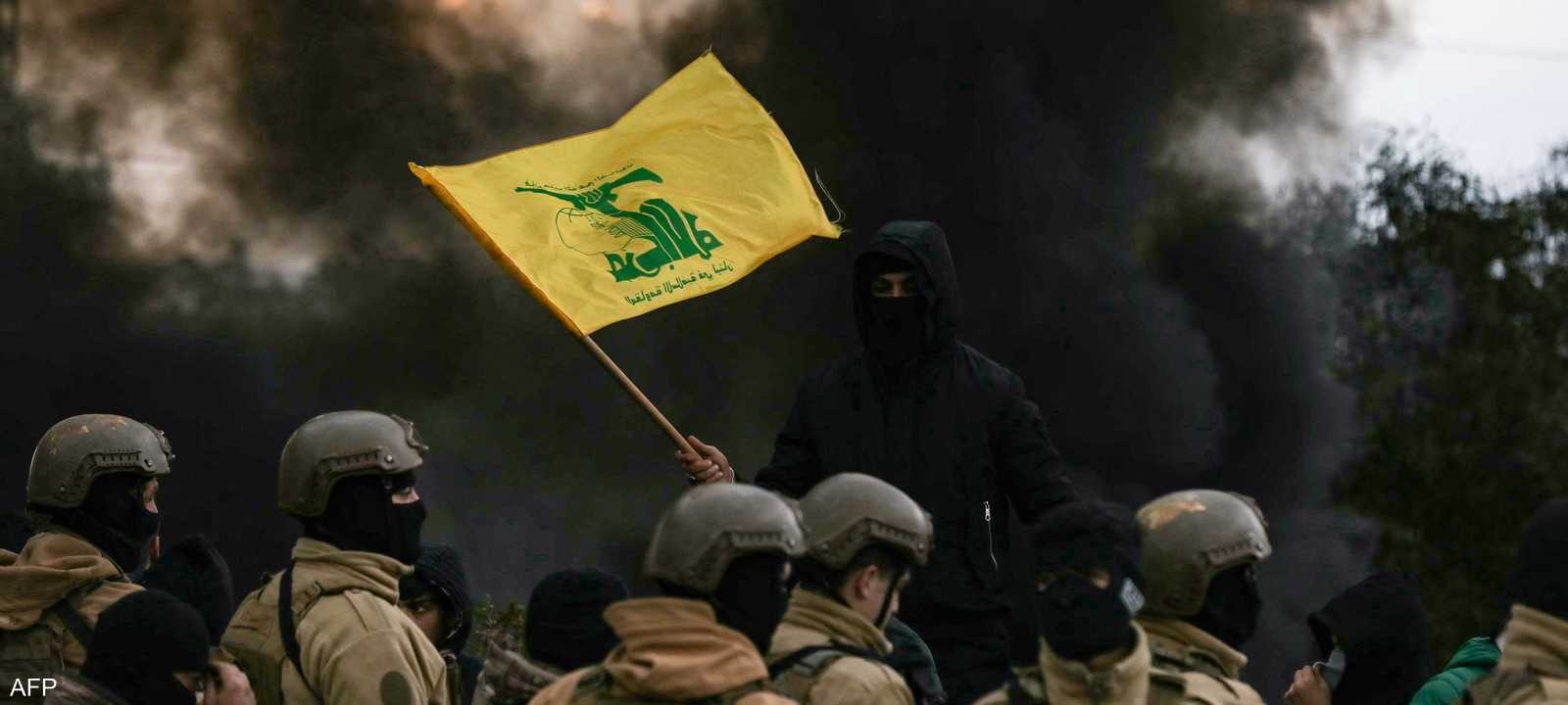 أحد مؤيدي حزب الله يلوح بعلم الحزب أمام جنود الجيش اللبناني،